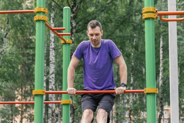Obraz premium Man exercising dips on outdoor bar in park