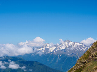 Fototapeta premium Majestic mountain peaks capped with snow and washed by clouds create a breathtaking wilderness landscape