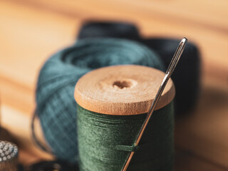 Close-up of a threaded needle and measuring tape against a background of fabrics, symbolizing the art of sewing and needlework