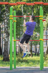 Athlete building strength with pull-ups on colorful workout equipment in park