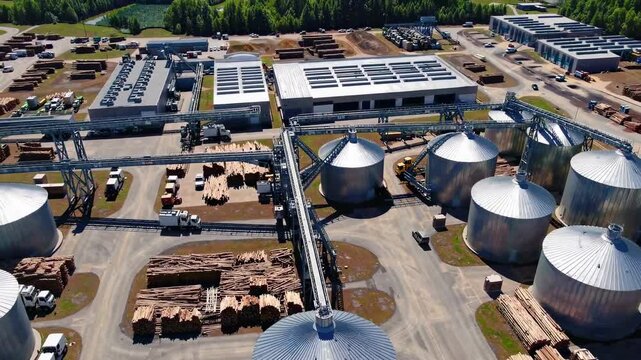 Industrial grain storage facility showcasing silos, transport systems, and lumber stacks in a bustling agricultural area