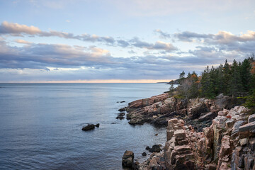 It is evening and the day begins to close. The ocean is quiet, and the rocky, granite shoreline...
