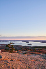 This sweeping view from Cadillac mountain in Acadia National Park shows the porcupine islands, the Atlantic ocean and the coastline of Maine. It is a beautiful scenic morning, with  a few pink clouds
