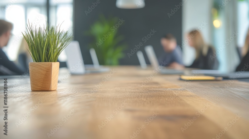 Poster small potted plant sits on a large wooden desk in a modern office with business people working on la