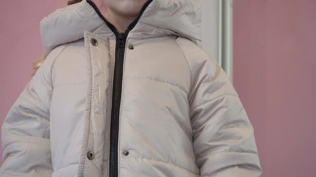 zipping up a winter jacket, little girl zipping up a beige winter jacket, putting on outer winter clothing