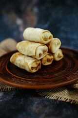 Stack of golden brown pancakes on a dark wooden plate with burlap decor