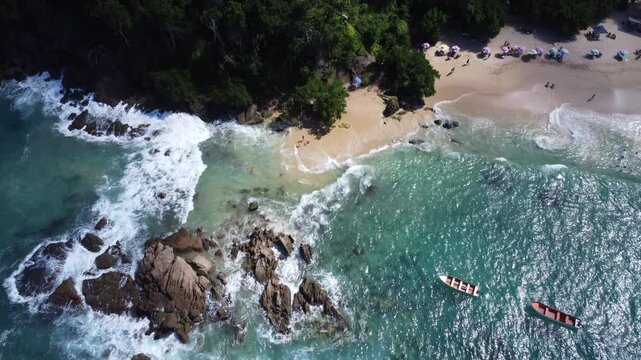 Aerial view of Mono Manso Beach, a secluded tropical paradise near Chuspa, Venezuela &ndash; Lush green forest, rocky shoreline, golden sand, and crystal-clear turquoise water