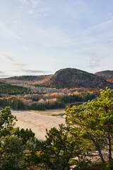 An elevated view on a beautiful autumn day, looking down on Sand beach and the nearby Beehive mountain. It is near the end of fall, and many of the leaves are still on the trees.