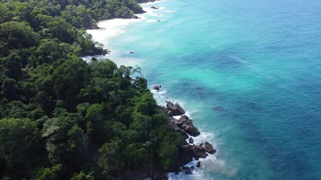 Aerial view of Mono Manso Beach, a secluded tropical paradise near Chuspa, Venezuela &ndash; Lush green forest, rocky shoreline, golden sand, and crystal-clear turquoise water