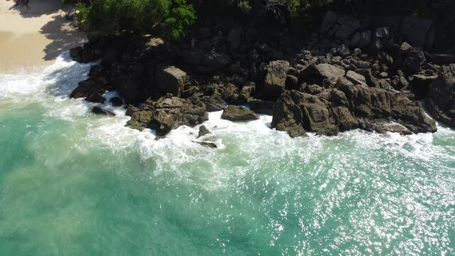 Aerial view of Mono Manso Beach, a secluded tropical paradise near Chuspa, Venezuela &ndash; Lush green forest, rocky shoreline, golden sand, and crystal-clear turquoise water