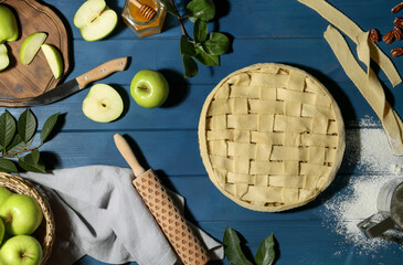 Uncooked homemade apple pie and ingredients on blue wooden table, flat lay