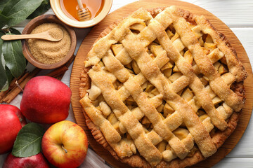 Tasty homemade apple pie and ingredients on white wooden table, flat lay