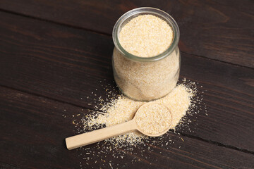 Oat bran in glass jar and spoon on wooden table
