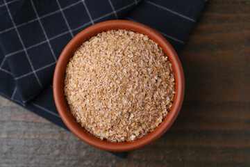 Buckwheat bran in bowl on wooden table, top view