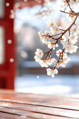 Spring blossoms on wooden table, snowing, blurred Asian temple background; perfect for greeting cards, calendars, or websites
