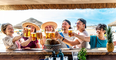 Multi generation friends cheering beer glasses together outside at the beach chiringuito - Happy family people celebrating summertime in open brewery pub - Beverage event and happy lifestyle concept