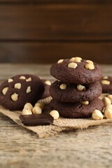 Tasty chocolate cookies with hazelnuts on wooden table, closeup