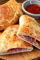 Pieces of calzone pizza served on wooden table, closeup