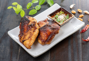 A plate of grilled chicken with a spicy dipping sauce.