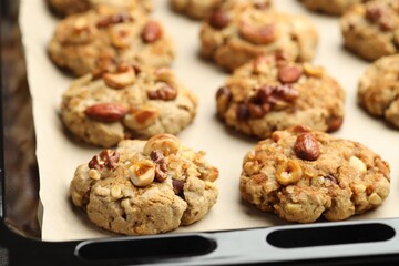 Tasty cookies with nuts in baking tray, closeup