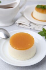 Tasty pudding with caramel sauce served on white table, closeup