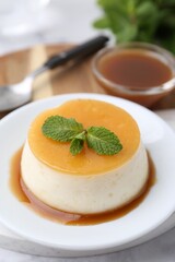 Tasty pudding with caramel sauce served on white marble table, closeup
