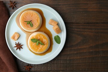 Tasty puddings with caramel sauce served on wooden table, flat lay. Space for text