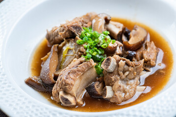 A bowl of pork ribs soup with mushrooms and spring onions.
