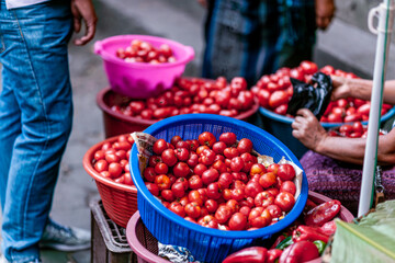 Vibrant colors are displayed on the food and clothing of the vendors. Delicious fruit is sold on the street.