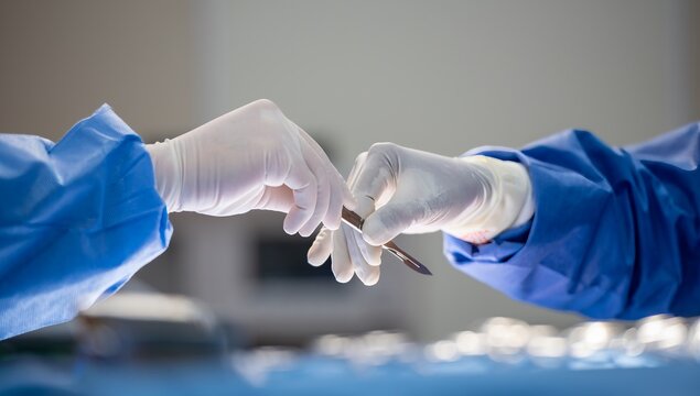 Team of surgery doctor in Operating Room hold hands scalpel surgical blade give to Surgeons During Operation. surgeons assistance in green gown coat give scalpel surgical blade to doctor