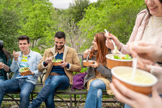 Group of friends enjoying take-away food in plastic-free bowls outdoors