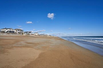 Seabrook beach during off-season in October. It is a sunny day on the sandy beach, but there are no people to be seen. A row of vacation cottages line the beach.