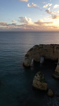Dramatic coastal sunset with rocky archway and ocean waves