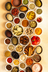 Assorted spices and herbs on a beige background, offering rich scents and vibrant colors, ideal for adding depth and warmth to any culinary creation