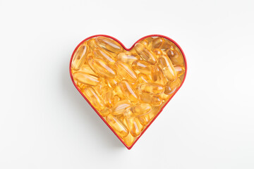 The heart made of yellow capsules of vitamin Omega 3 or D on a white background. Yellow pills of fish oil. Preventing heart disease and ischemic stroke. Skin care, depression treatment
