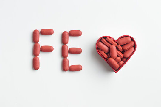 Chemical element letters Fe made of pills, flat lay on a white background. Medicinal pills and capsules for health, dietary supplements and vitamin iron Fe for iron deficiency anemia prevention