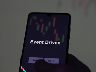 An investor analyzing the event driven etf fund on a screen. A phone shows the prices of Event Driven