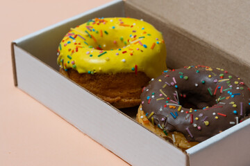 Close up of colorful donuts in box on orange background.