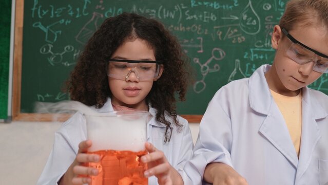 Closeup of Energetic cute girl inspect solution while looking at sample. Curious american student standing at blackboard with chemical theory while doing experiment and discovery new sample. Pedagogy.