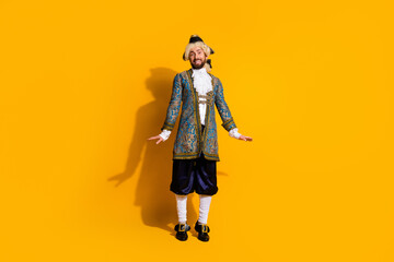 A cheerful man poses in ornate vintage royal costume on a vibrant yellow background, exuding festive energy