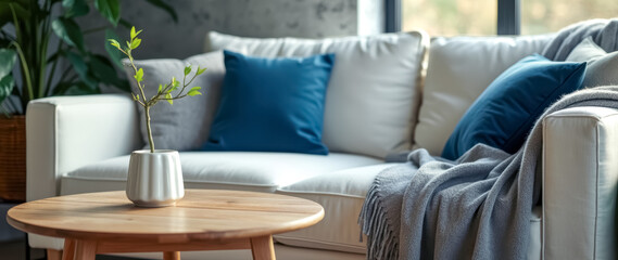 small green plant a white vase sits on a wooden coffee table front a white couch.