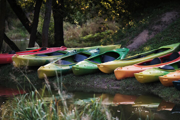 Many canoes of different colors on the river bank before training without people. Boating on the city river