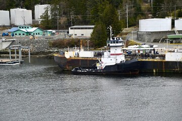 An oil barge and a tugboat are docked at a fuel terminal in Ketchikan, Alaska