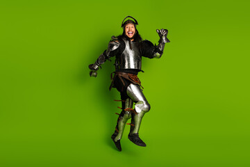 Young Medieval Knight in Steel Armor Leaping Joyfully on Bright Green Background