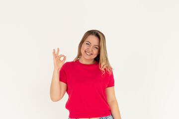 Fototapeta premium Young beautiful woman wearing red t-shirt over isolated white background smiling positive doing ok sign with hand and fingers. Successful expression.
