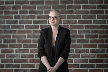 Obraz premium Confident Woman in Professional Attire Sitting in Photography Studio. Female cancer survivor. Smiling Woman with Glasses Posing Confidently in a Studio Environment. Model Has Glaucoma