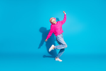 Young woman in vibrant pink pullover striking a playful pose against a bright blue background