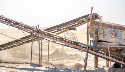 Vibrating screen stone crusher in operation. Crushing stones in a quarry for processing minerals, cement, limestone. Heavy and mobile equipment in a quarry for processing stone into building material.