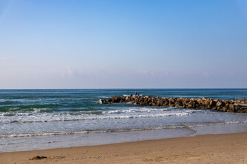 Fishermen in the distance on a breakwater made of large boulders in the Mediterranean Sea