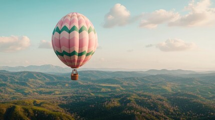 Fototapeta premium A colorful hot air balloon floats above rolling hills and valleys, surrounded by a serene sky, creating a picturesque and tranquil scene.